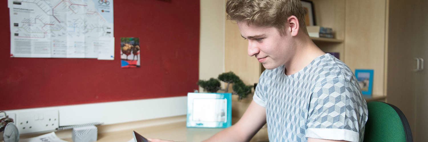 A student sitting at his desk in the student accommodation, Queen Margaret University