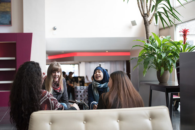 A group of students sit talking and laughing on sofas, Queen Margaret University, Edinburgh