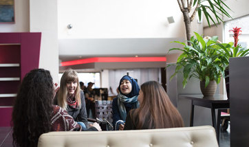 A group of students sit talking and laughing on sofas, Queen Margaret University, Edinburgh