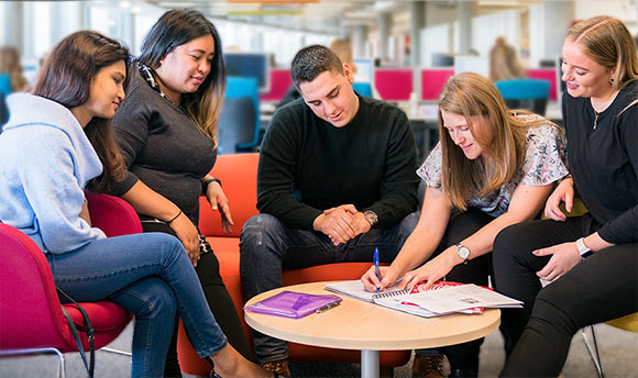 A group of Queen Margaret University students sitting together round a table, Edinburgh