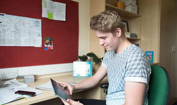 A student sitting at his desk in the student accommodation, Queen Margaret University