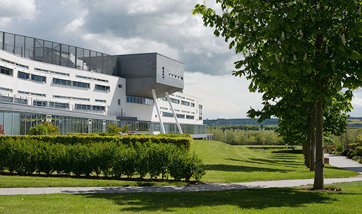 A view of Queen Margaret University Campus from outside with foliage in the foreground