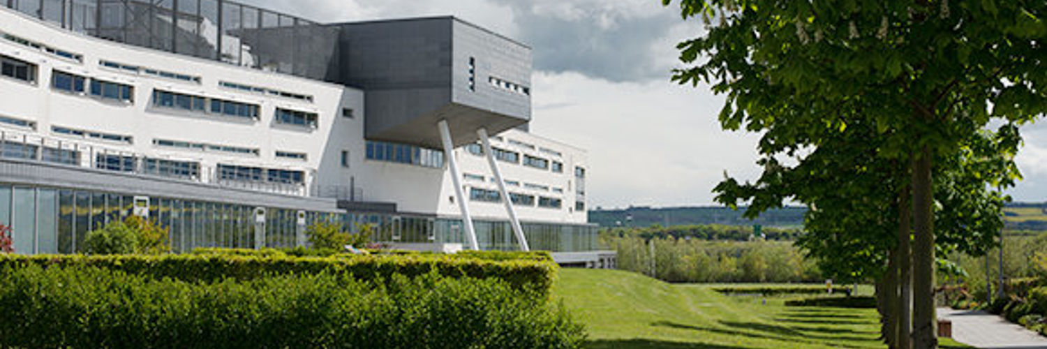 A view of Queen Margaret University Campus from outside with foliage in the foreground
