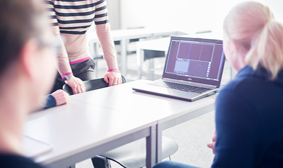 A group of students crowded round a laptop, Queen Margaret University, Edinburgh