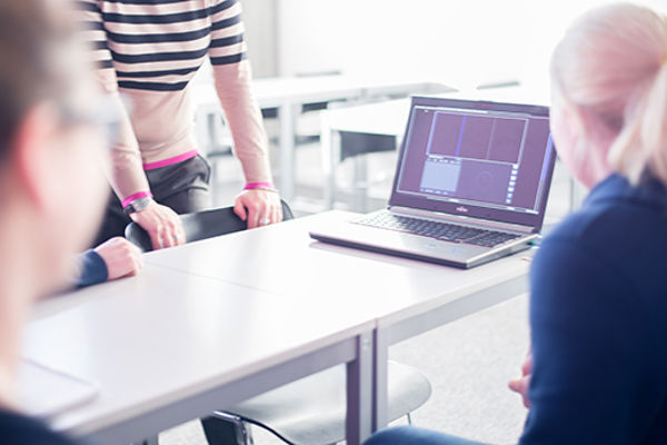 A group of students crowded round a laptop, Queen Margaret University, Edinburgh