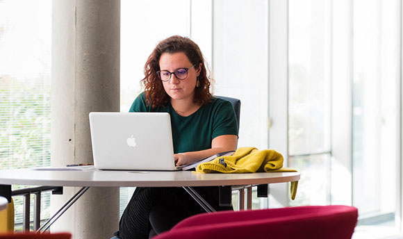 A young woman working intently on a Macbook laptop, QMU, Edinburgh