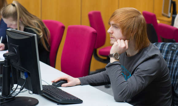 A Queen Margaret University student working alone at their computer desk, Edinburgh