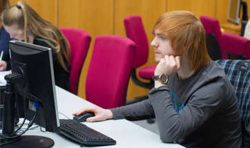 A Queen Margaret University student working alone at their computer desk, Edinburgh
