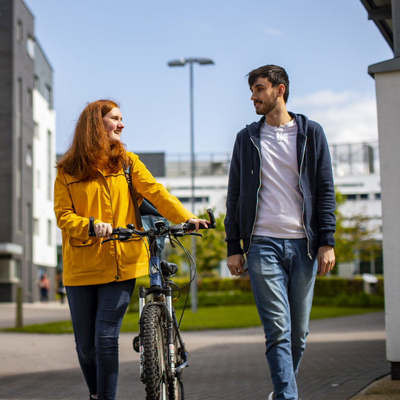 Two students walking in the sunshine and talking
