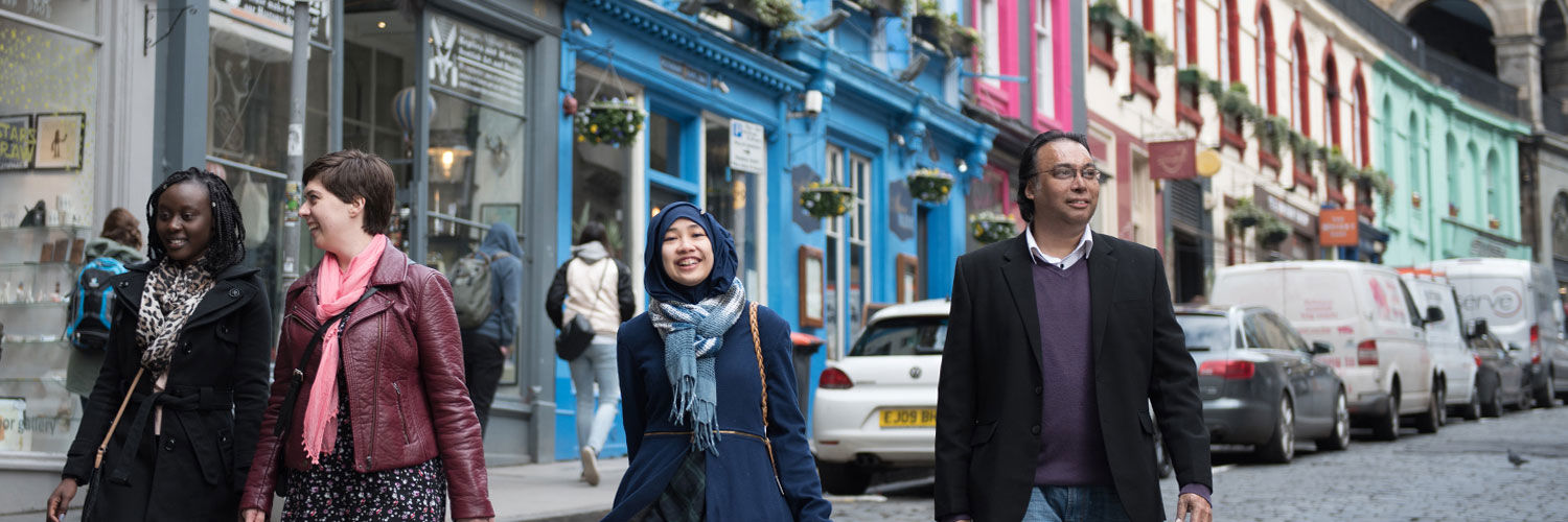 Pedestrians walking down Victoria Street with its brightly painted buildings, Edinburgh