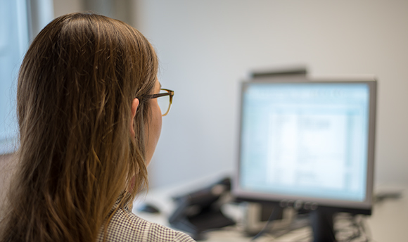 The back of a person's head and the blurry screen of their desktop in front of them