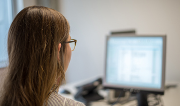 The back of a person's head and the blurry screen of their desktop in front of them