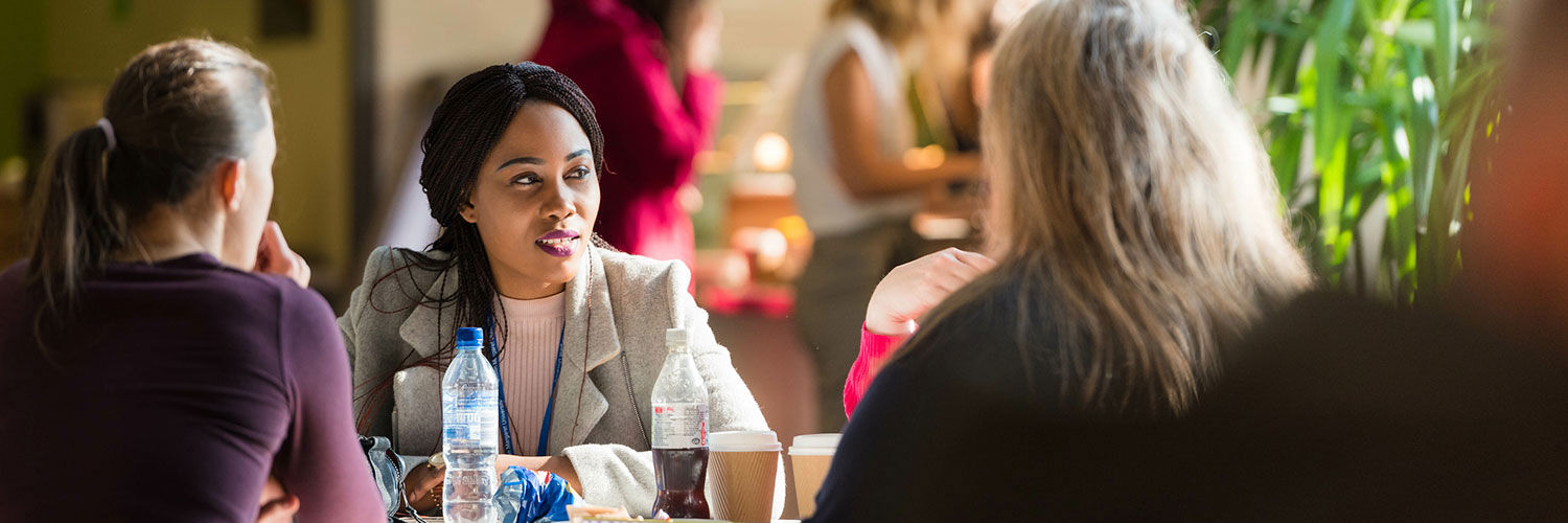 A group of women sat round a table in the Master's Cafe, talking and enjoying drinks