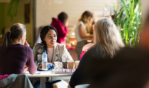 A group of women sat round a table in the Master's Cafe, talking and enjoying drinks