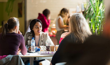 A group of women sat round a table in the Master's Cafe, talking and enjoying drinks