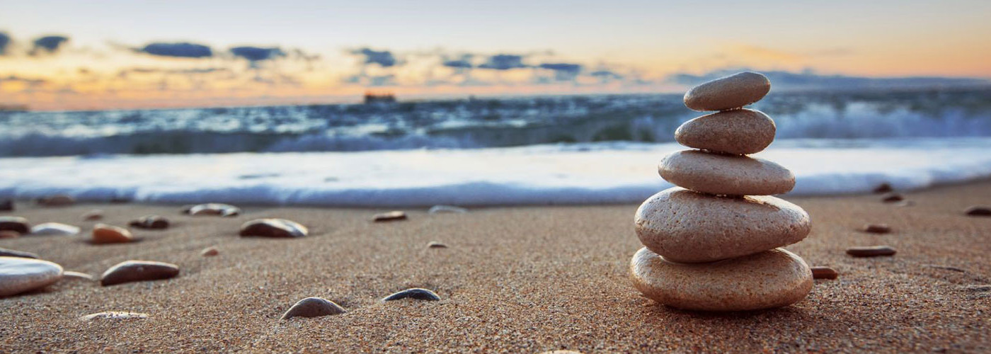 Close up of pebbles stacked up on a beach, with the sea and sky in the background