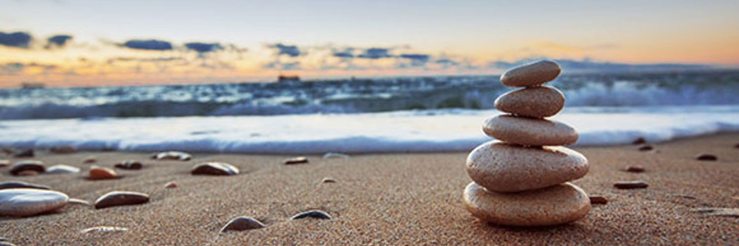 Close up of pebbles stacked up on a beach, with the sea and sky in the background