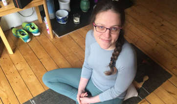 Kate brown sitting cross legged on a yoga matt at home