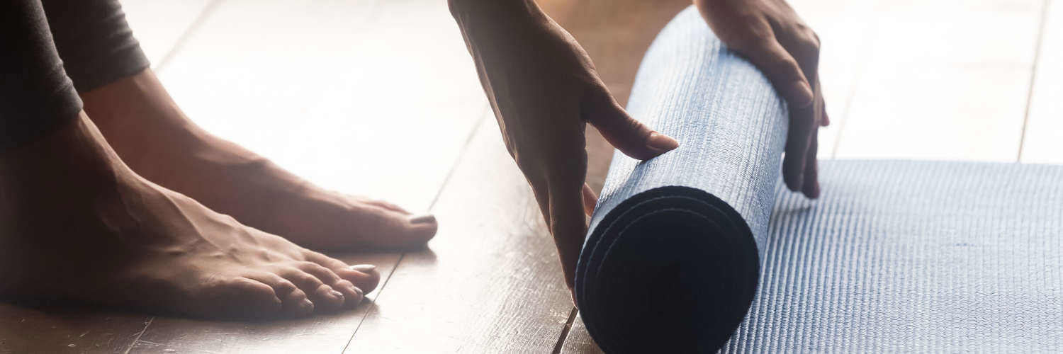 Close up of someone barefoot rolling up a yoga matt