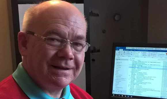 Malcolm Cutt sitting by his computer in his home office, Edinburgh