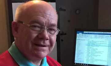 Malcolm Cutt sitting by his computer in his home office, Edinburgh