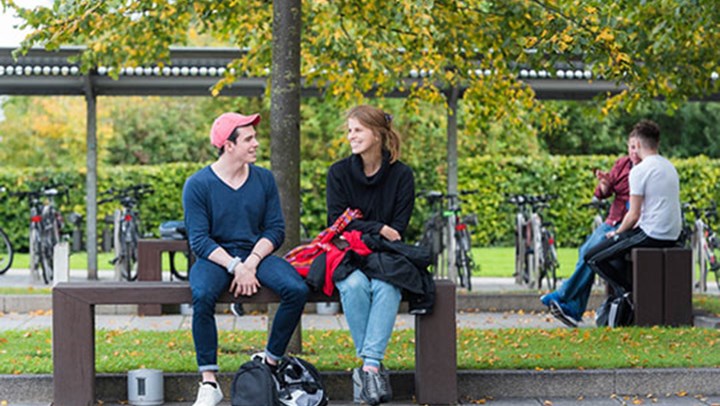 QMU students chatting and smiling on a bench outside, Edinburgh