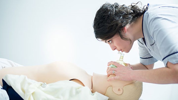 A student nurse practicing mouth to mouth resuscitation on a CPR Annie doll
