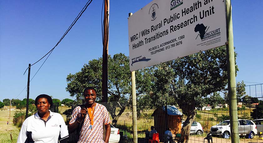 A pair of smiling people beside the Wits Rural Public Health Unit in South Africa