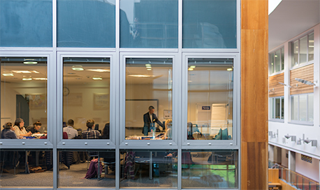 A class being taught photographed from outside through a wall of windows, QMU