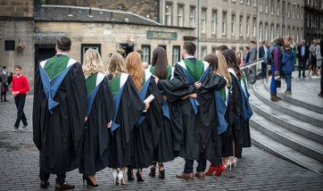 A row of QMU graduands standing in a row wearing their gowns outside Usher Hall