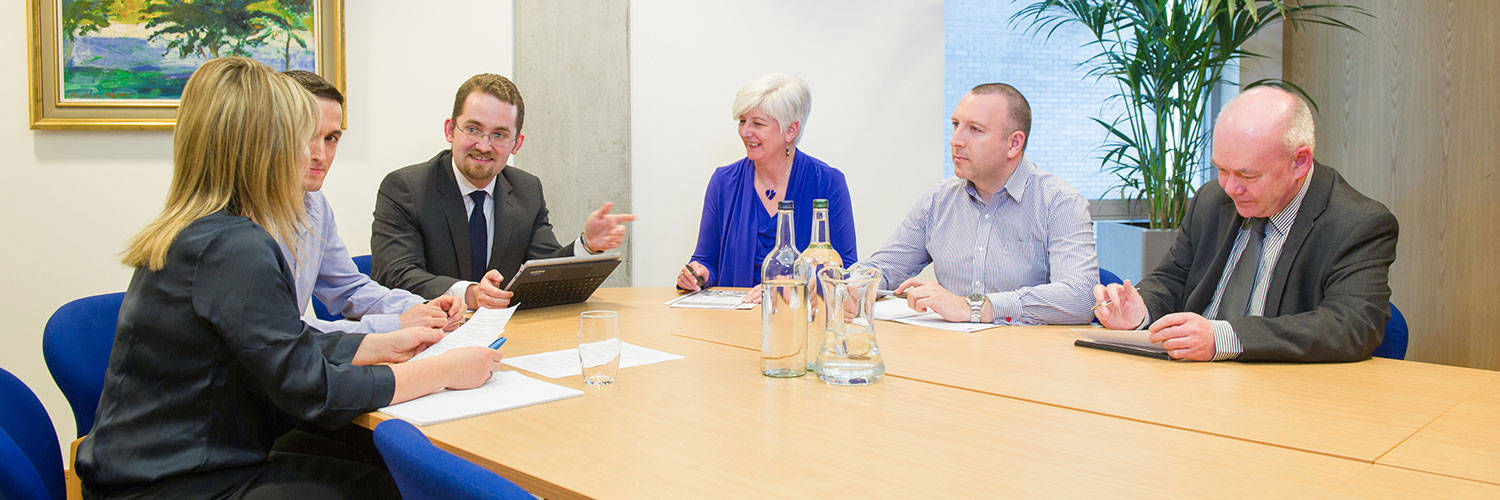 A committee meeting taking place at a board room table 