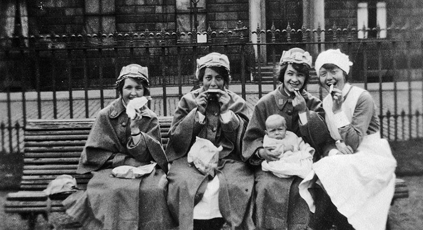 B+W photo of women on a bench eating lunch and smiling at the camera