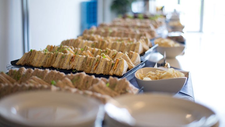 A buffet table with trays of sandwiches and crisps