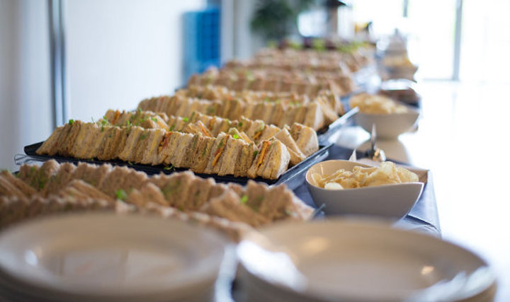 A buffet table with trays of sandwiches and crisps