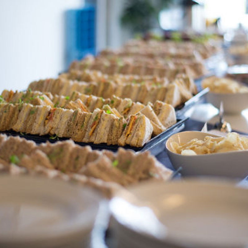 A buffet table with trays of sandwiches and crisps