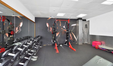 A bright, modern weights room in the gym with a large variation in weights & a squat rack
