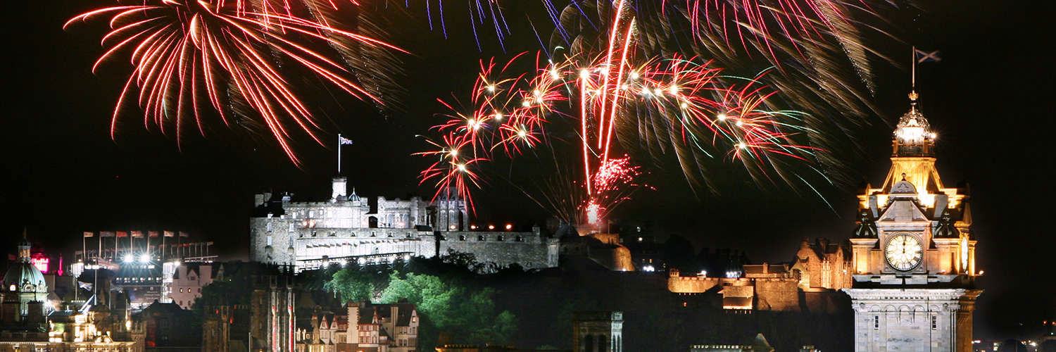 Fireworks setting off above Edinburgh Castle at night time