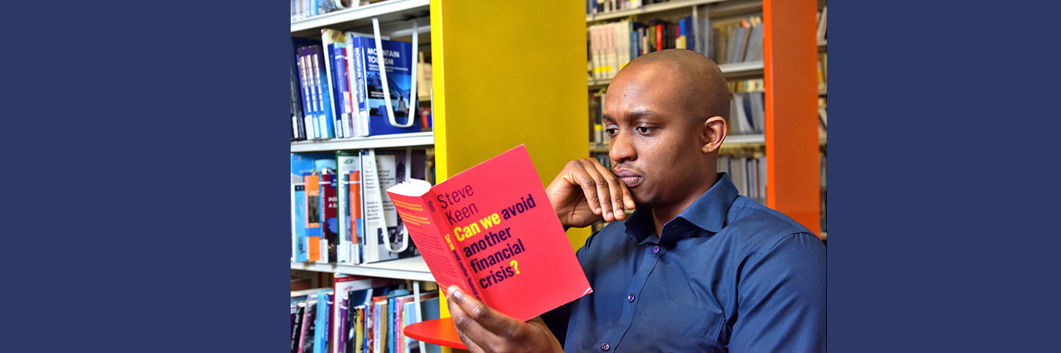 A QMU student reading a book about financial crisis in library