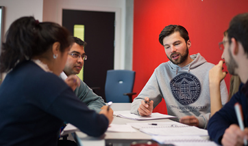 Group of  QMU students talking round a table and taking notes