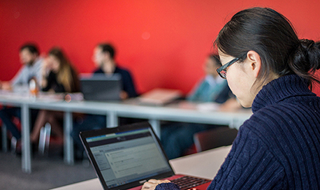 Business Management student sitting in class on their laptop