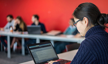 Business Management student sitting in class on their laptop