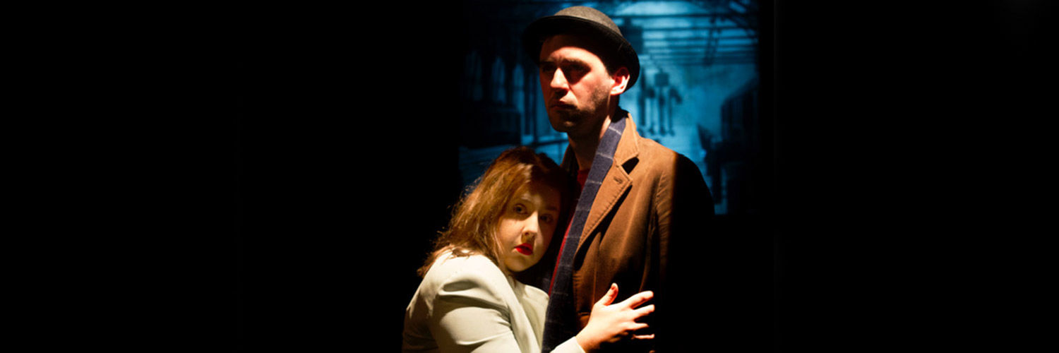 A woman clutching to a mysterious man on stage