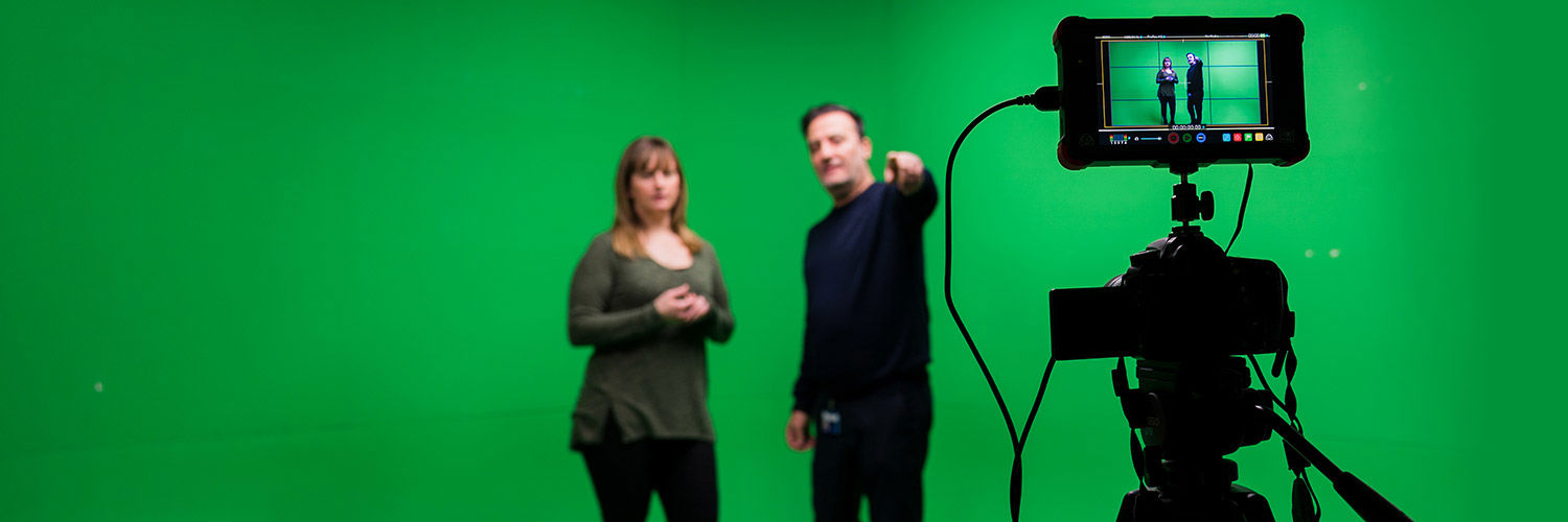 A Queen Margaret University student being briefed in front of a green screen