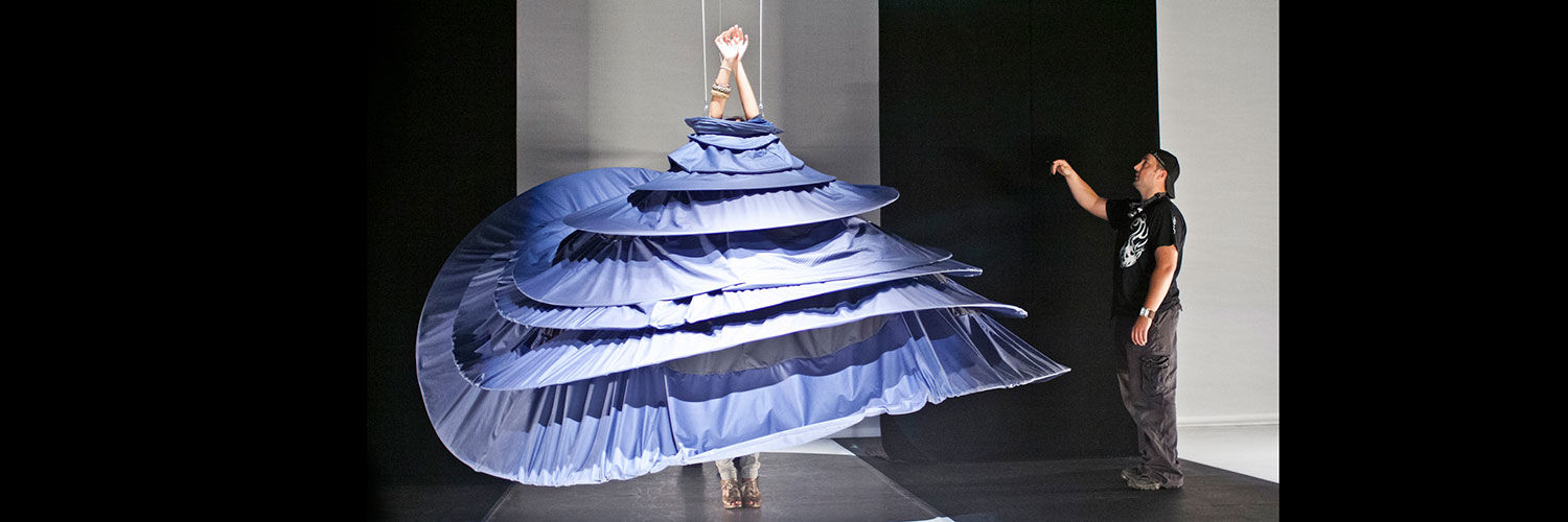 A fashion student on a runway wearing an exaggeratedly large dress