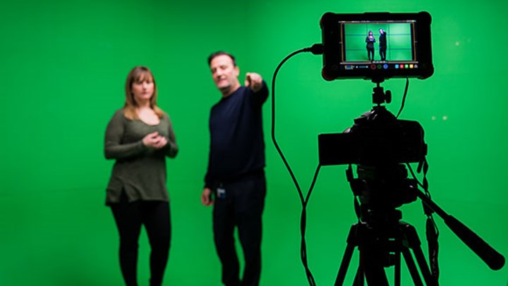 A Queen Margaret University student being briefed in front of a green screen