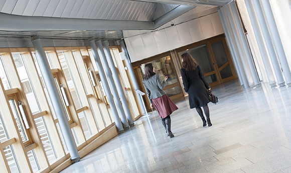 Two women walking down a corridor in Queen Margaret University hallway