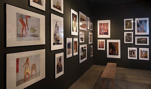 A room with black walls covered in framed photographs with varying subject matter