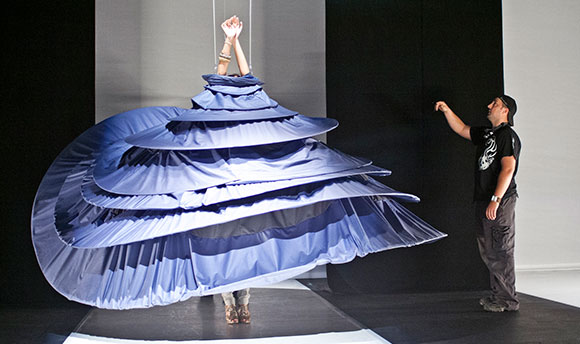 A fashion student on a runway wearing an exaggeratedly large dress