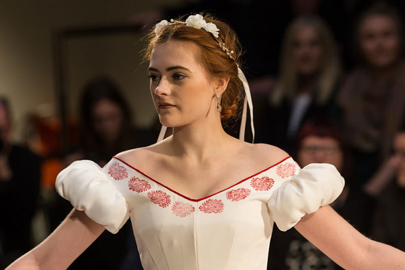 Model wearing white puff-sleeved dress and flower hairband
