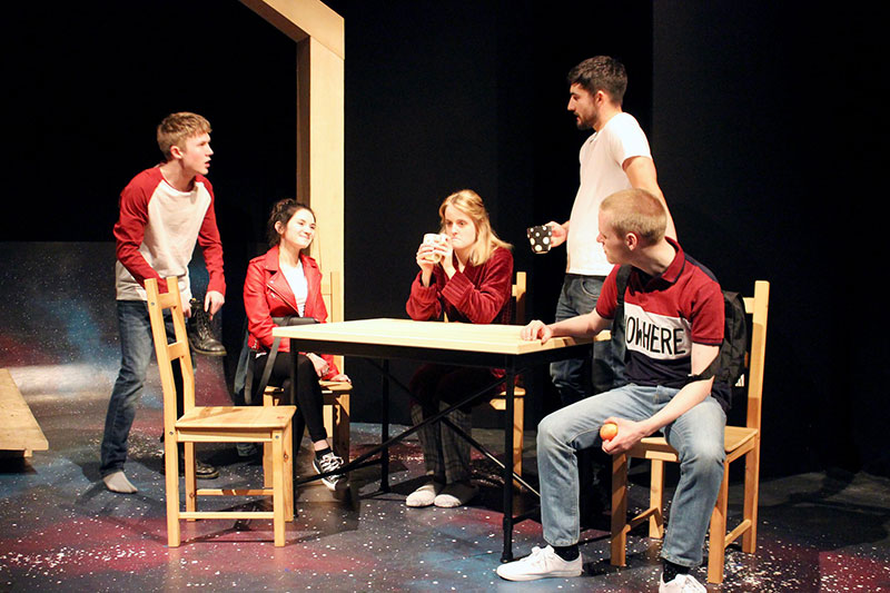 A group of QMU drama students around a table on a stage